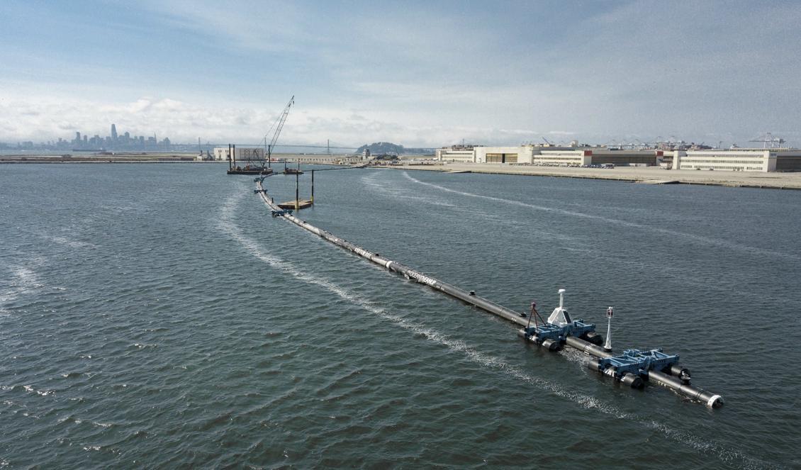 Den långa, flytande bommen dras ut från land för att släppas på havet mellan USA och Hawaii. Foto: The Ocean Cleanup/TT