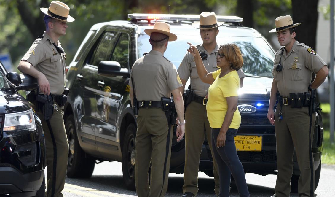 En privatperson talar med poliser som samlats i närheten av platsen för skottlossningen i Maryland. Foto: Steve Ruark/AP/TT