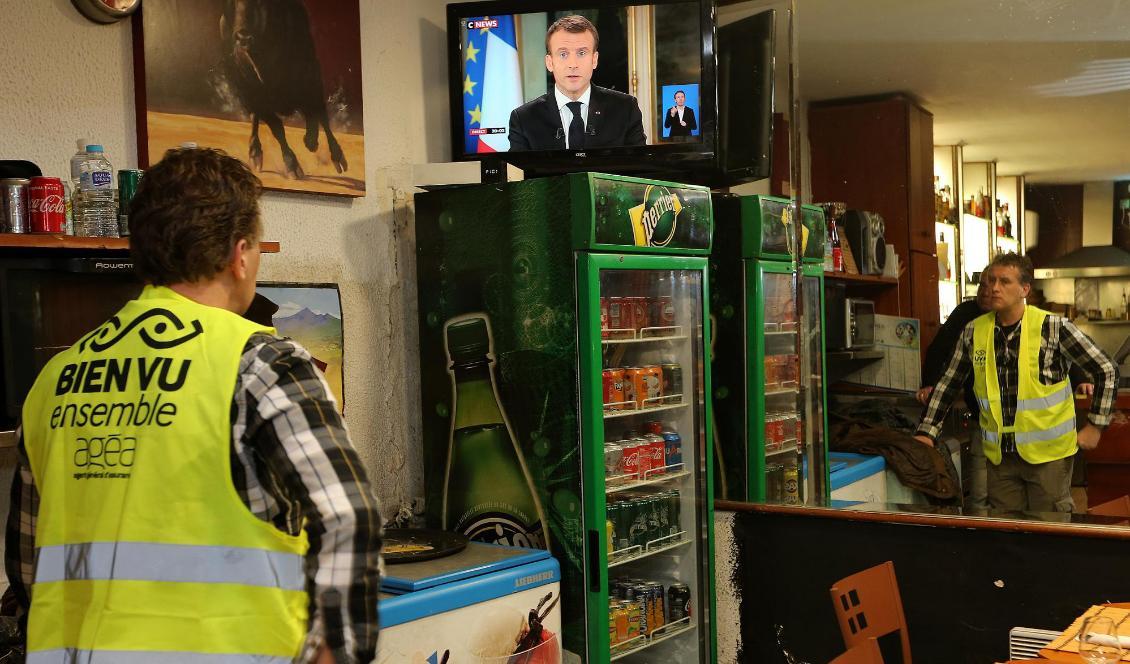 
En anhängare till Gula västarna tittar på president Emmanuel Macrons tv-sända tal på måndagkvällen. Foto: Bob Edme/AP/TT                                                