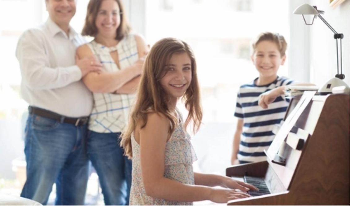 En glad familj samlad runt pianot.