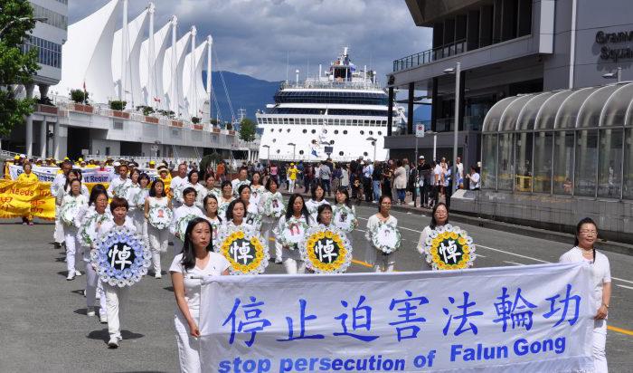 Falun Gong-utövare  håller minnesbilder av utövare som dött i tortyr och förföljelse i Kina, under en parad i Vancouver 16 juli 2017. Foto: Tang Feng, Epoch Times.