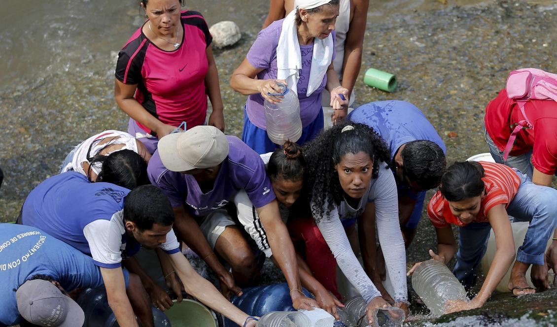 Människor samlar vatten ur en trasig vattenledning i Venezuelas huvudstad Caracas. Foto: Fernando Llano/AP/TT