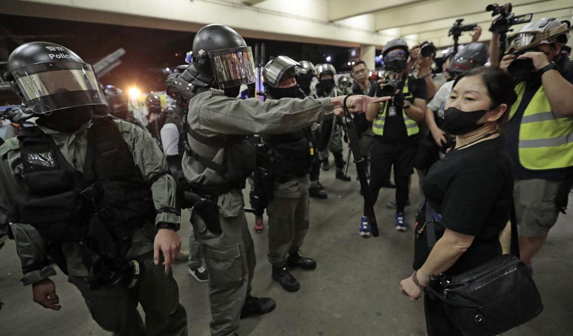 Kravallpolis säger åt en kvinna att ta av sin ansiktsmask under protesterna i söndags. Foto: Dita Alangkara/AP/TT
