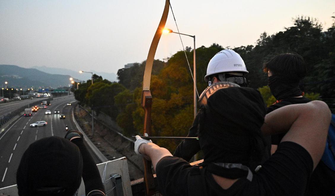 Demonstranter använder pilbåge för att få bort bilar på en motorväg utanför Chinese University of Hong Kong (CUHK) i Hongkong den 13 vovember 2019. Foto: Philip Fong/AFP via Getty Images