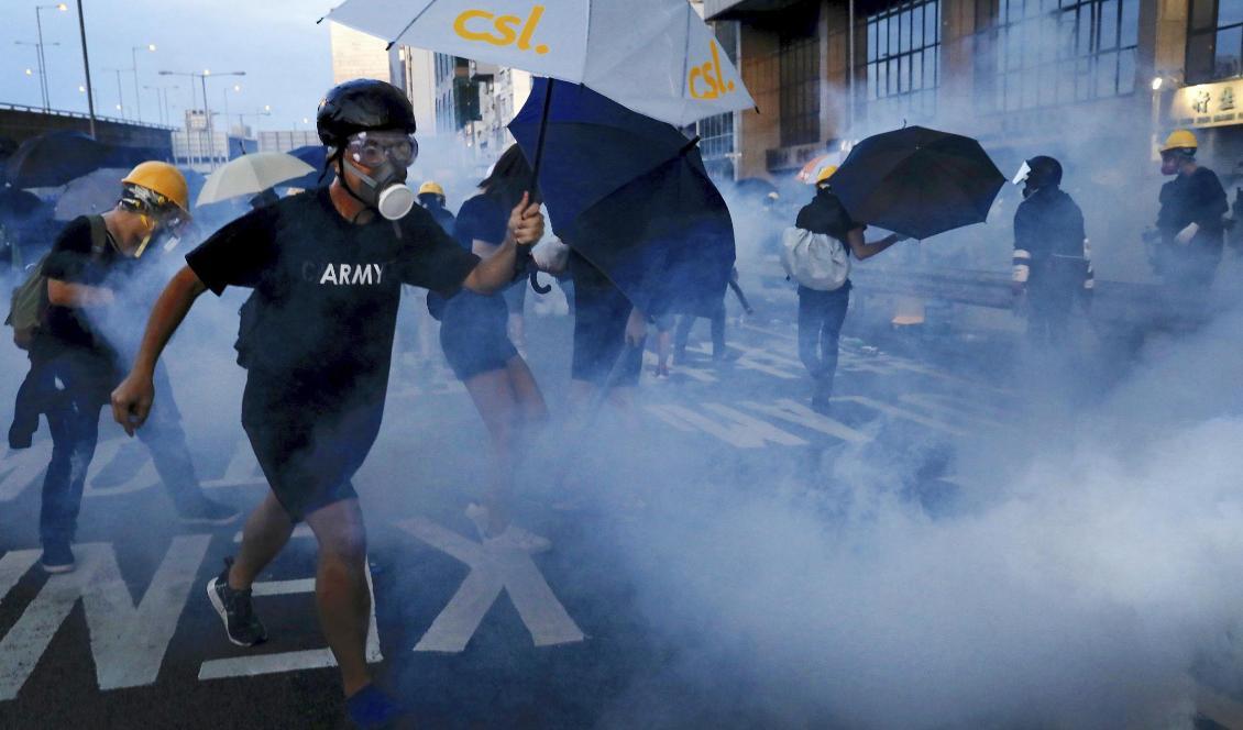 Demonstranter i Hongkong skyddar sig från polisens tårgas med hjälp av paraplyer. Foto: Vincent Yu/AP/TT