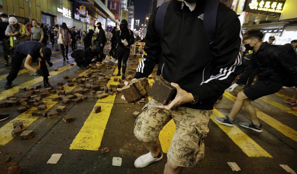Demonstranter gräver upp gatstenar i Hongkong under söndagens nya protester i staden. Foto: Dita Alangkara/AP/TT