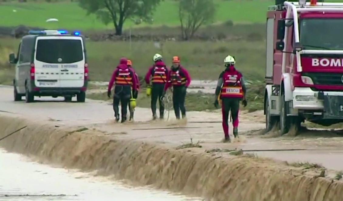 Personal från räddningstjänsten nära platsen där två personer omkom i en vattenfylld bil sydost om staden Valencia. Foto: Atlas/AP/TT