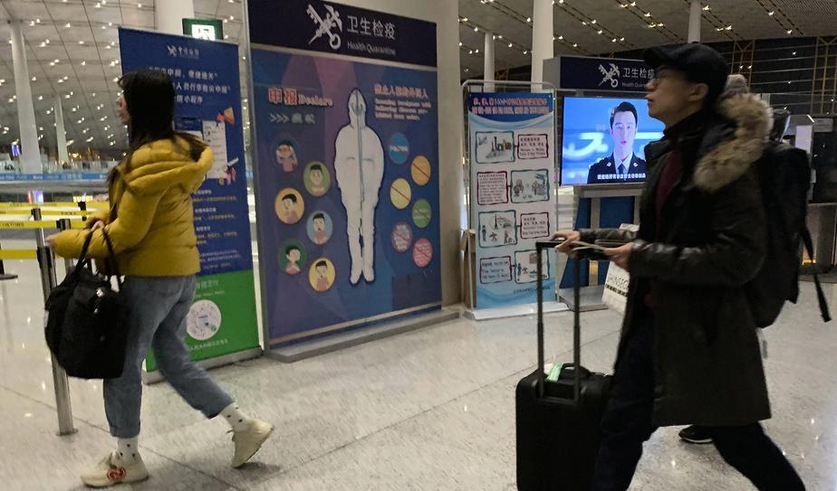 Resenärer passerar en hälsokontroll vid den internationella flygplatsen i Peking. Bilden togs den 13 januari. Foto: Ng Han Guan/AP/TT
