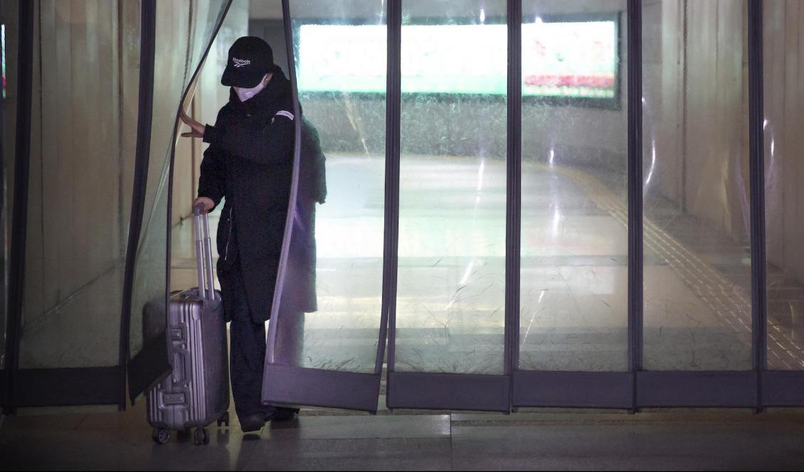 En person med ansiktsmask vid en tunnelbanestation i Kinas huvudstad Peking på söndagen. Foto: Mark Schiefelbein/AP/TT