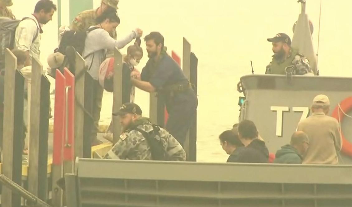 Människor evakueras från Mallacoota med marinens fartyg. Foto: Channel 9/AP/TT