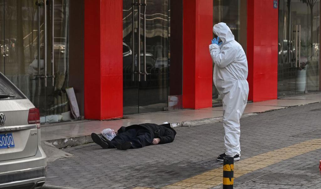 En tjänsteman i skyddsdräkt kontrollerar en man som kollapsat på gatan och dött nära ett sjukhus i Wuhan, den 30 jan. 2020. Foto: Hextor Retamal, AFP via Getty Images
