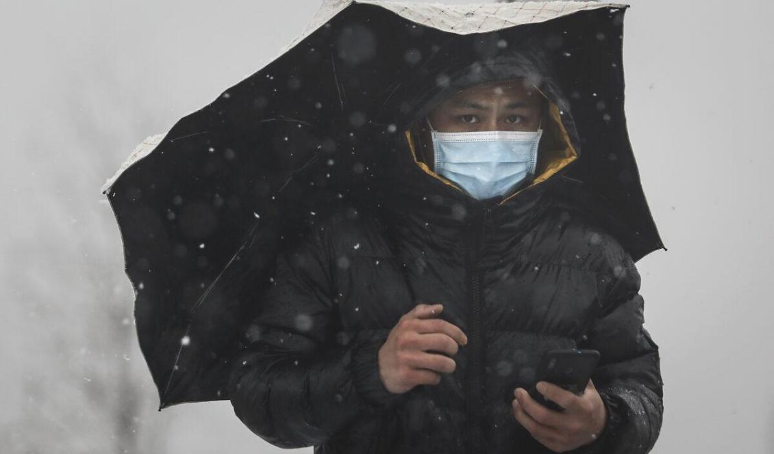 En man i skyddsmask går i snöfallet över en bro över floden Yangzi, i Wuhan, Kina, den 15 februari 2020. Foto: Getty Images