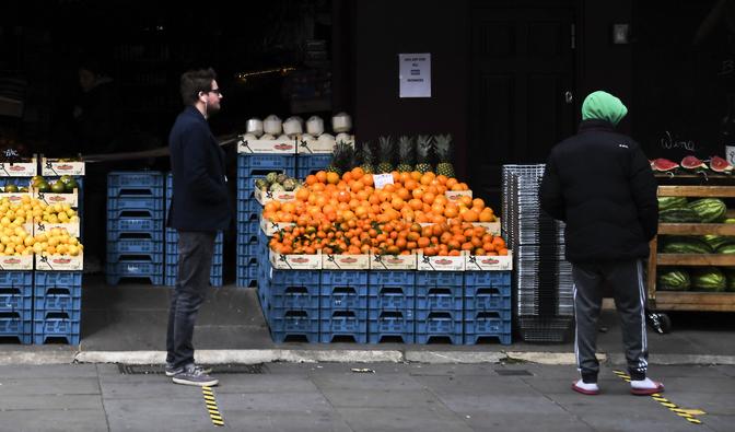 Britterna uppmanas att hålla sig inomhus, men de får gå ut för att köpa mat. Men då ska de hålla två meters avstånd. Här syns folk köa med avstånd utanför en livsmedelsbutik i London. Foto: Alberto Pezzali/AP/TT