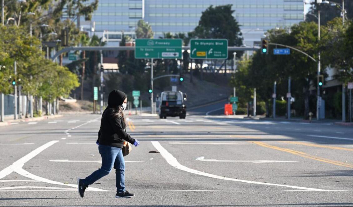 

En kvinna i munskydd korsar gatan i Los Angeles, USA, den 30 mars 2020. Foto: Robyn Beck/AFP via Getty Images                                                                                                