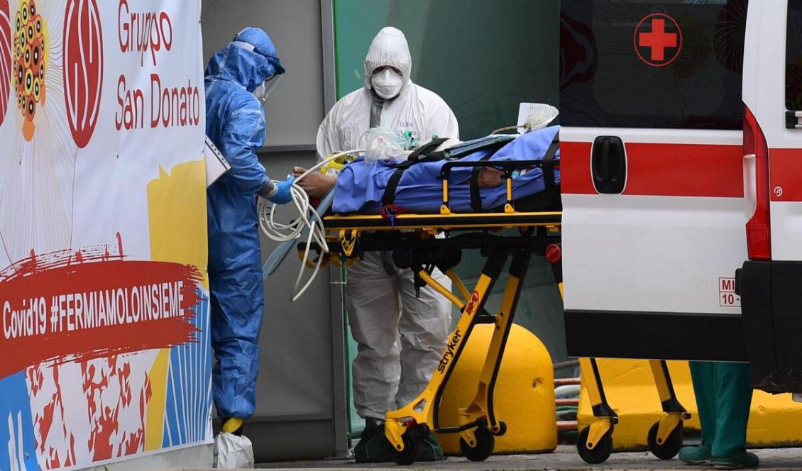 Sjukvårdspersonal hjälper en patient från ambulansen till en akutvårdsenhet i en sporthall utanför San Raffaele-sjukhuset i Milano, den 23 mars 2020. Foto: Miguel Medina/AFP via Getty Images