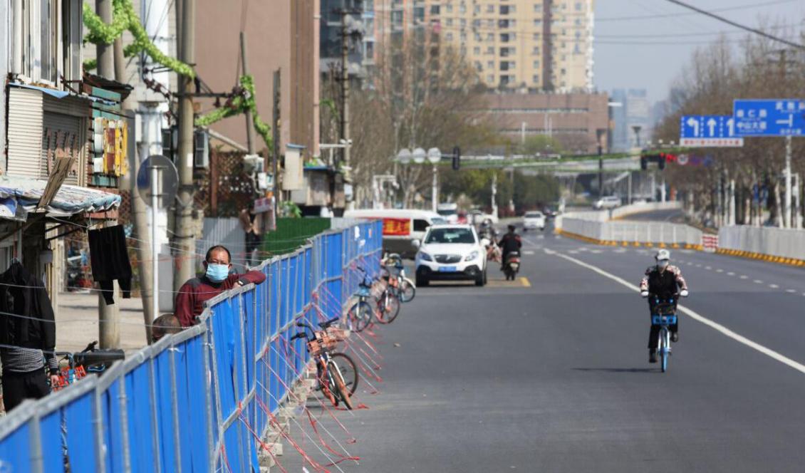 En man tittar över barrikaden som satts upp för att människor inte ska gå in i eller ut ur husen i Wuhan, den 17 mars 2020. Foto: STR/AFP via Getty Images