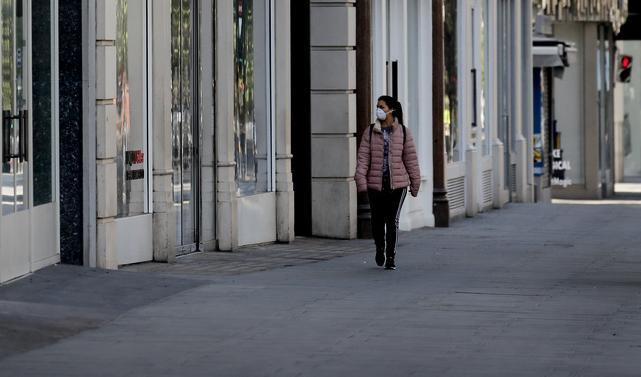 Oxford Street i London i veckan. En ensam kvinna med munskydd går för de stängda butikerna. Foto: Frank Augstein/AP/TT