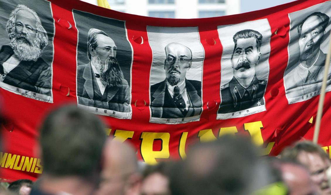 Demonstranter håller upp en banderoll med bilder på de stora kommunisterna, från vänster, Karl Marx, Friedrich Engels, Lenin, Stalin och Mao Zedong under en förstamajparad på Berlin's Alexanderplatz, den 1 maj 2005 i Berlin, Tyskland. 