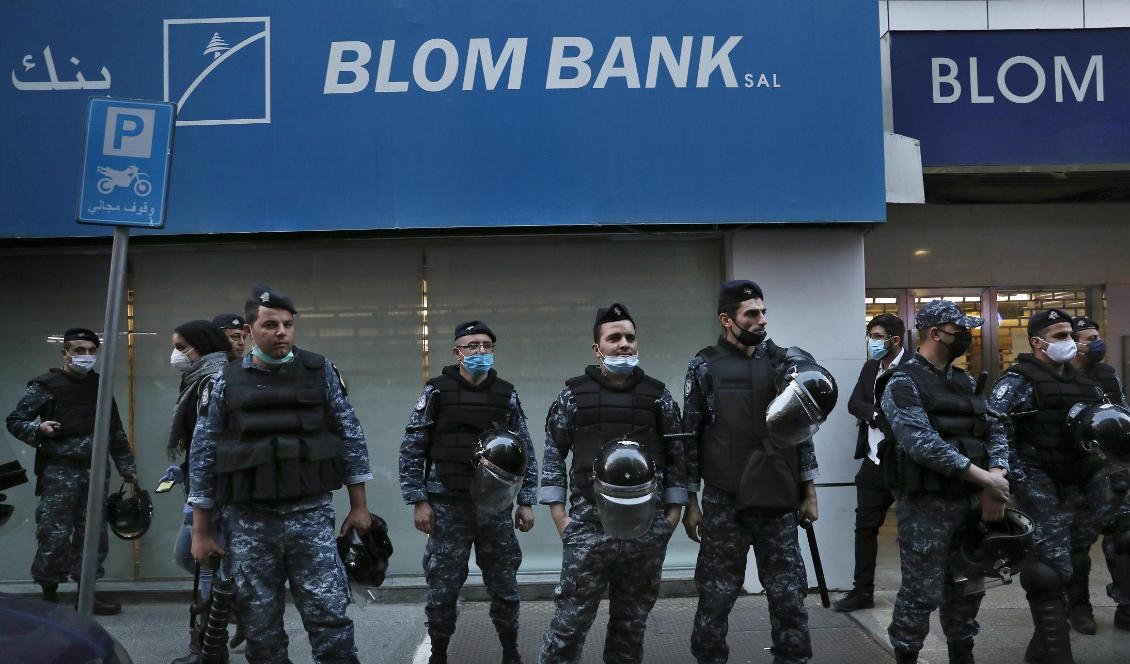 Bankerna ses som en symbol för den finansiella och ekonomiska krisen och blir ofta en måltavla för demonstranters ilska i Libanon. Bilden är tagen i Beirut i förra veckan, då kravallpolis under en protest ställde upp utanför en bank i området Hamra. Foto: Hussein Malla/AP/TT-arkivbild