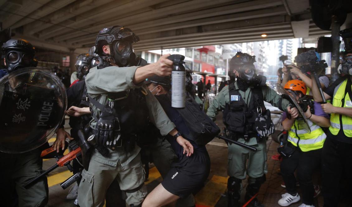 Kravallpolis sprutar pepparsprej mot demonstranter i stadsdelen Causeway Bay i Hongkong. Foto: Kin Cheung/AP/TT