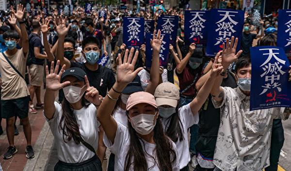 Under protester på Hongkongön, Hongkong, mot den nya säkerhetslagen håller människor upp fem fingrar för att symbolisera deras krav. På anslagen står "Himlen eliminerar KKP". Den 24 maj 2020. Foto: Anthony Wallace/AFP via Getty Images