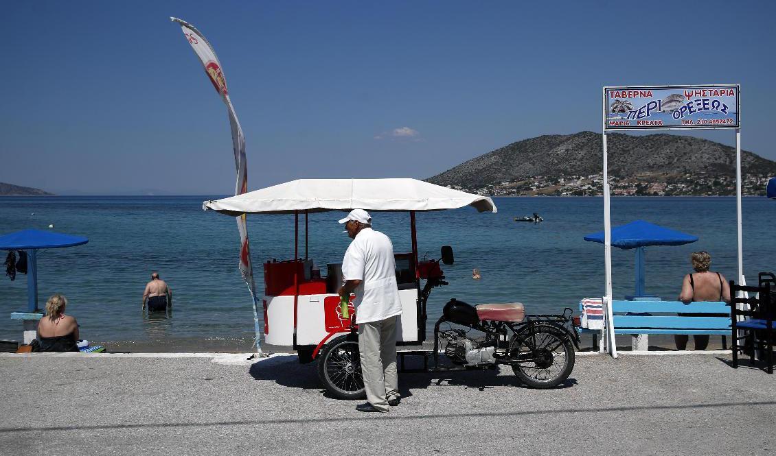 En glassförsäljare i väntan på kunder på ön Salamina strax väster om Aten på måndagen. Foto: Thanassis Stavrakis/AP/TT