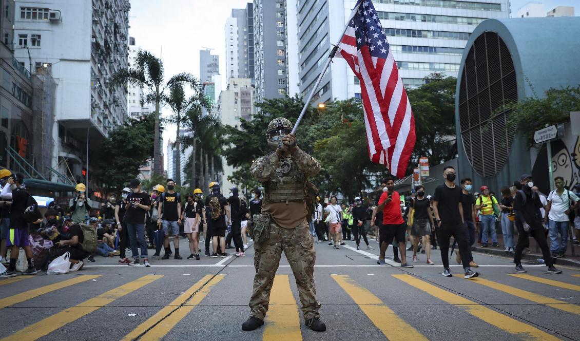 En demonstrant utklädd till militär håller en amerikansk flagga under demokratiprotester i Hongkong i augusti 2019. Foto: Vincent Thian/AP/TT