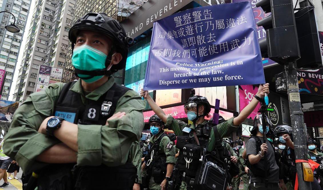Polis håller i en skylt som varnar för att det är olagligt att protestera i Hongkong. Foto: Vincent Yu/AP/TT