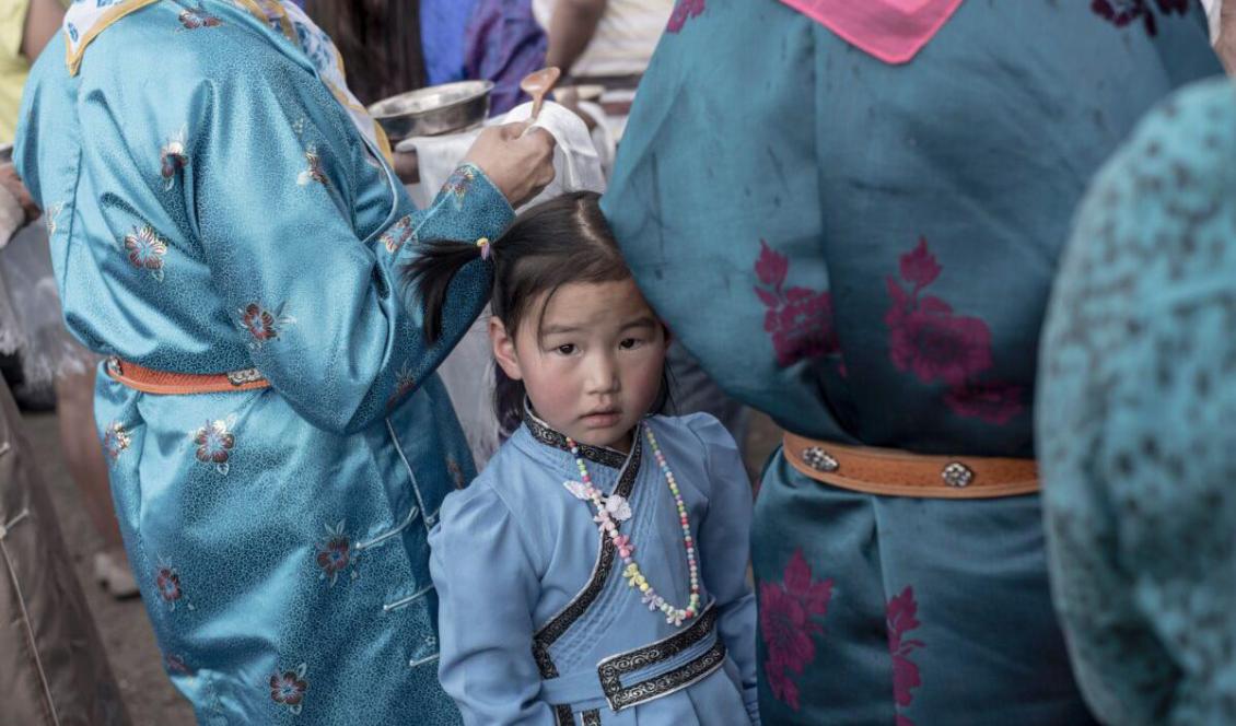 En flicka i traditionell, mongolisk dräkt väntar tillsammans med sin mamma i Ulan Bator, Mongoliet, den 23 juni 2017. Foto: Fred Dufour/AFP via Getty Images