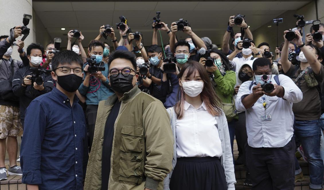 Joshua Wong (till vänster), poserar framför domstolsbyggnaden tillsammans med aktivisterna Ivan Lam och Agnes Chow, som också står inför rätta. Alla tre har erkänt sig skyldiga. Foto: Vincent Yu/AP/TT