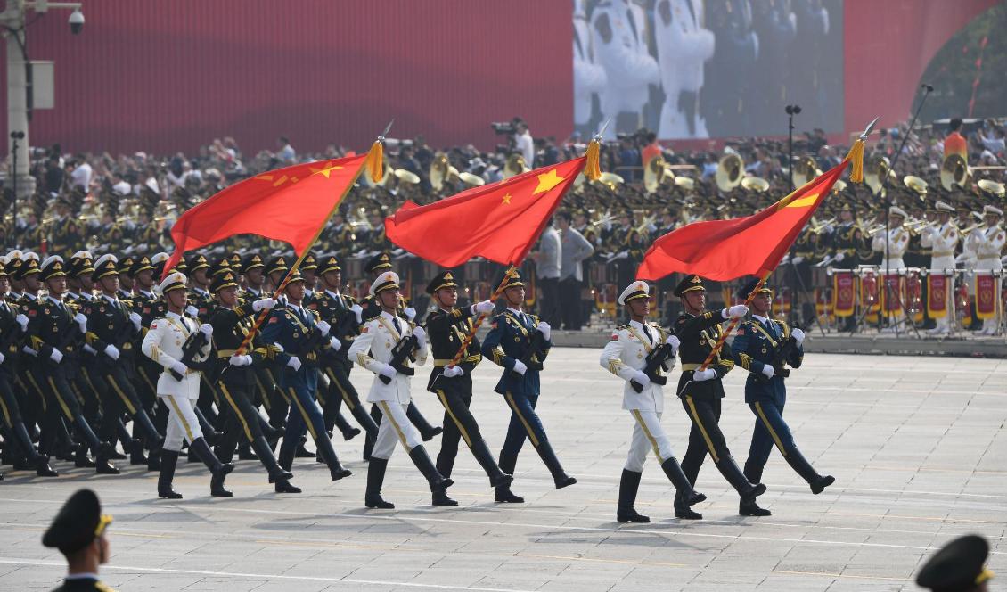 Kinesiska soldater marscherar med den kinesiska flaggan under en militärparad på Himmelska fridens torg i Peking, Kina, den 1 oktober 2019. Foto: Greg Baker/AFP via Getty Images