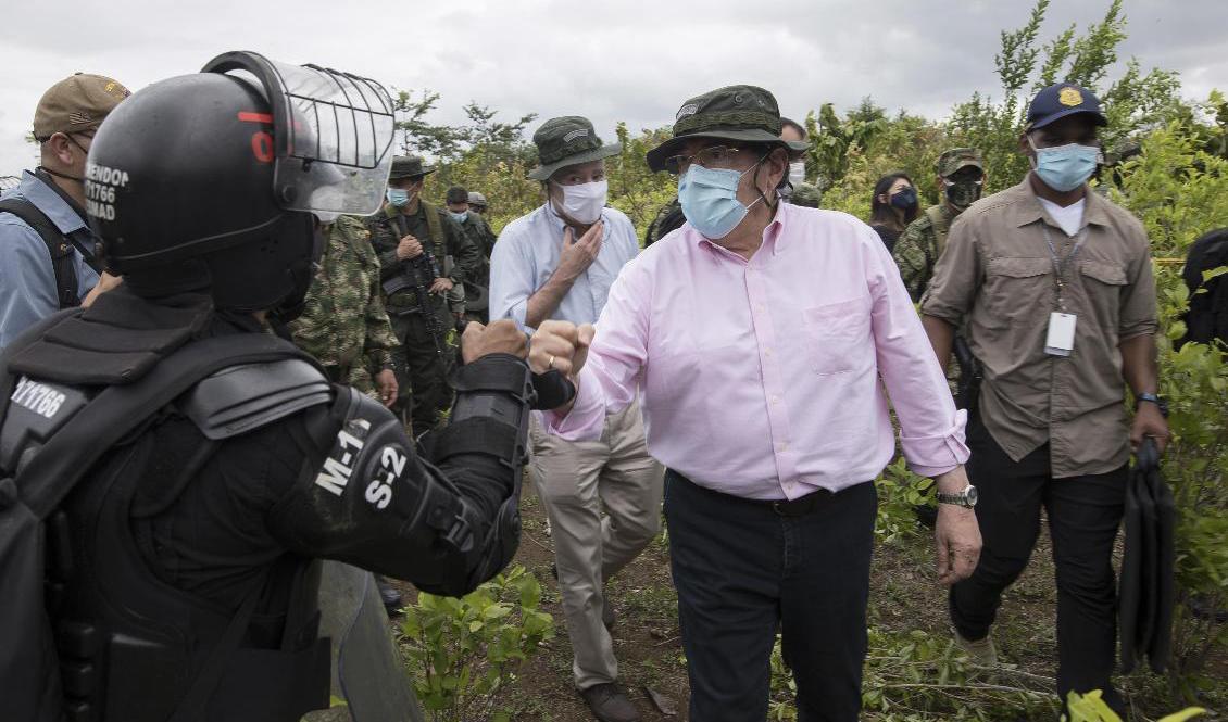 Colombias försvarsminister Carlos Holmes Trujillo, här i rosa skjorta, har avlidit efter att ha insjuknat i covid-19. Här träffar han poliser vid en insats mot en kokainodling i landet, den 30 december. Arkivbild. Foto: Ivan Valencia/AP/TT