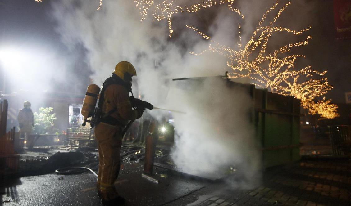 Räddningstjänsten släcker en container som satts i brand under protesterna mot utegångsförbudet. Foto: Peter Dejong/AP/TT
