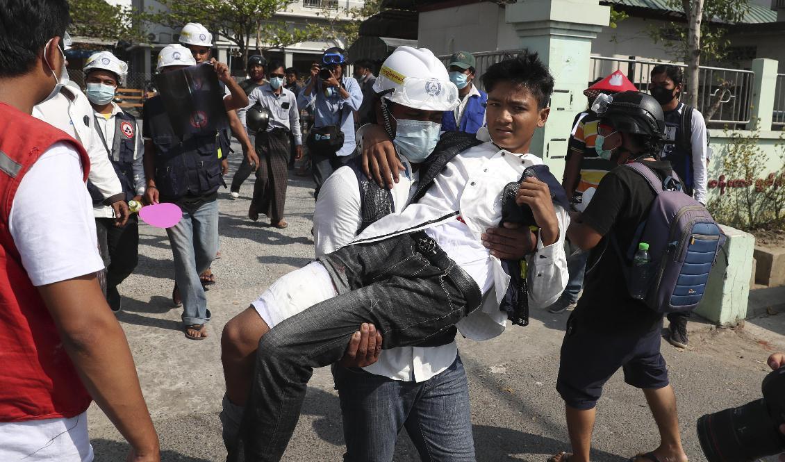 En skadad demonstrant bärs i väg av en meddemonstrant i Mandalay på söndagen. Foto: AP/TT