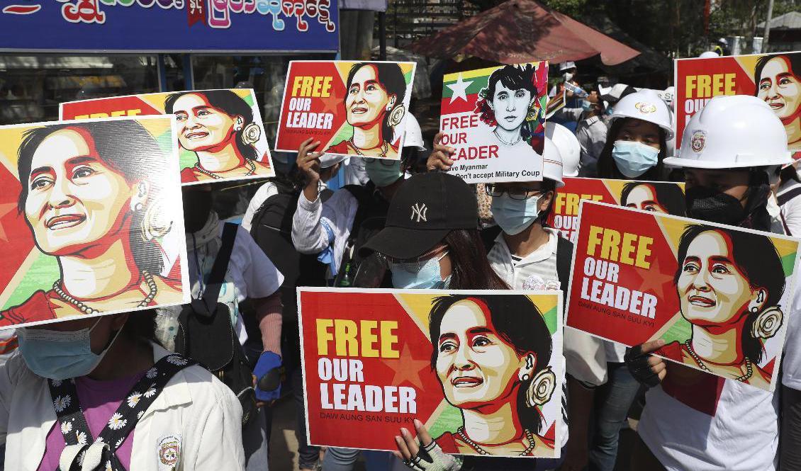 Demonstranter håller upp plakat med bilder på Myanmars avsatta civila ledare Aung San Suu Kyi under en protest mot militärjuntan i Mandalay i centrala Myanmar den 5 mars. Foto: AP/TT