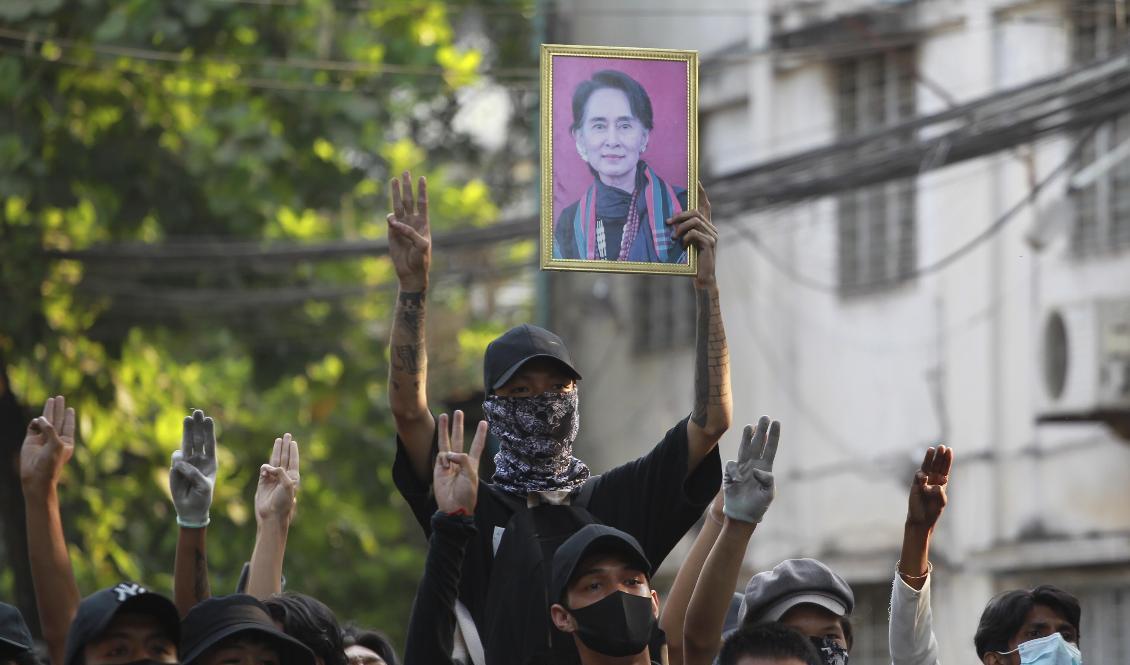 Ett porträtt av Myanmars störtade ledare Aung San Suu Kyi hålls upp vid en pro-demokratisk protest i storstaden Rangoon. Foto: AP/TT