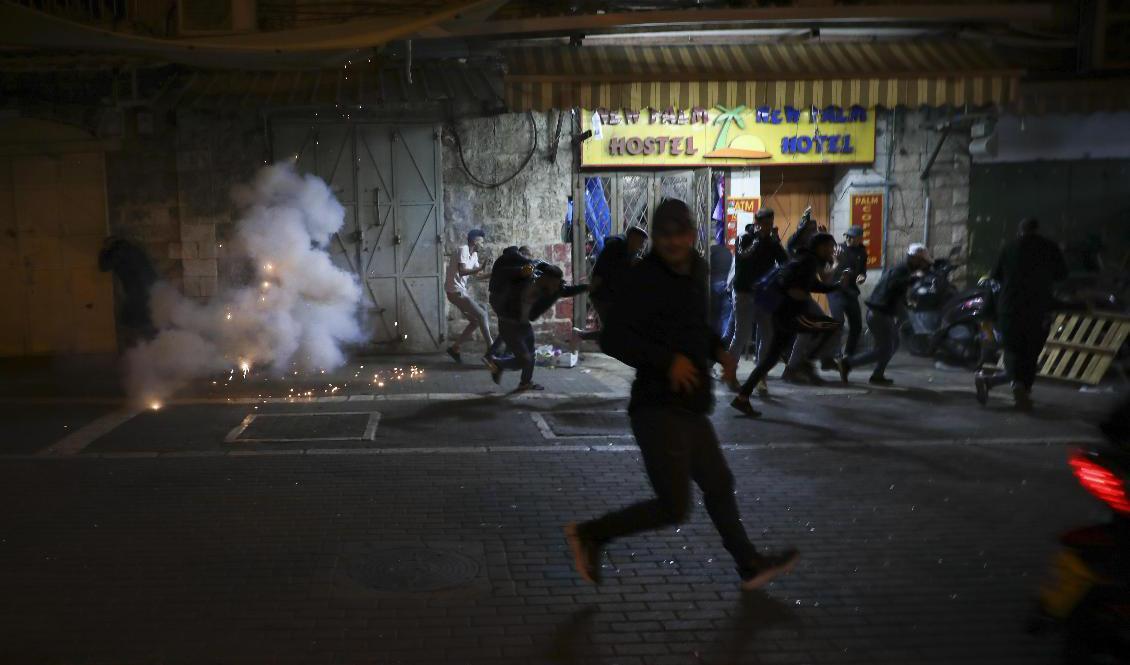 Palestinier flyr från polisens distraktionsgranater under sammandrabbningar i östra Jerusalem i torsdags kväll. Oroligheterna har fortsatt sedan dess. Foto: Mahmoud Illean/AP/TT