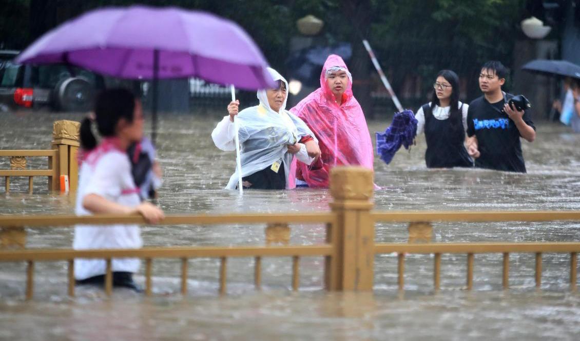 
Människor vadar genom Zhengzhous översvämmade gator. Foto: Chinatopix/AP/TT                                            