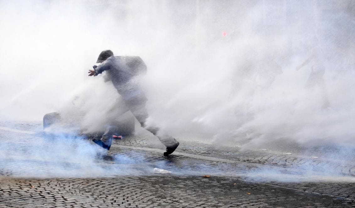 En fransman springer genom tårgas under protester mot Frankrikes obligatoriska vaccinationer för vissa yrkesgrupper och det obligatoriska vaccinationspasset. Den 21 juli 2021, Paris. Foto: Alain Jocard/AFP via Getty Images