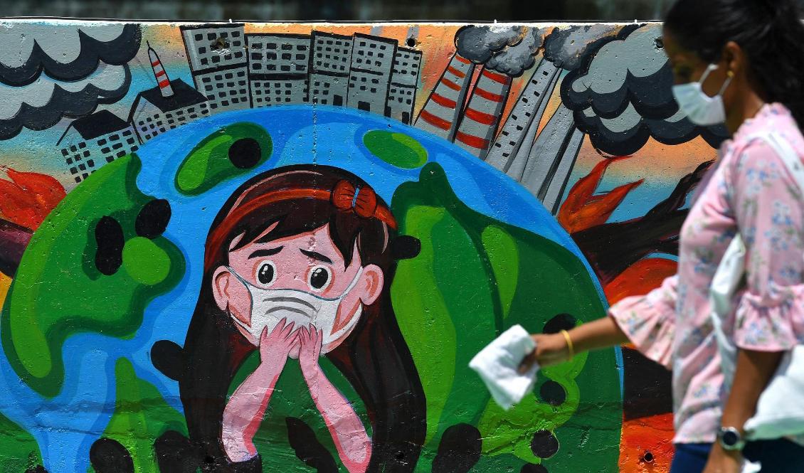 En kvinna går förbi en väggmålning som ska väcka uppmärksamhet kring frågan om luftföroreningar i Mumbai, Indien, den 13 juni 2021. Foto: INDRANIL MUKHERJEE/AFP via Getty Images