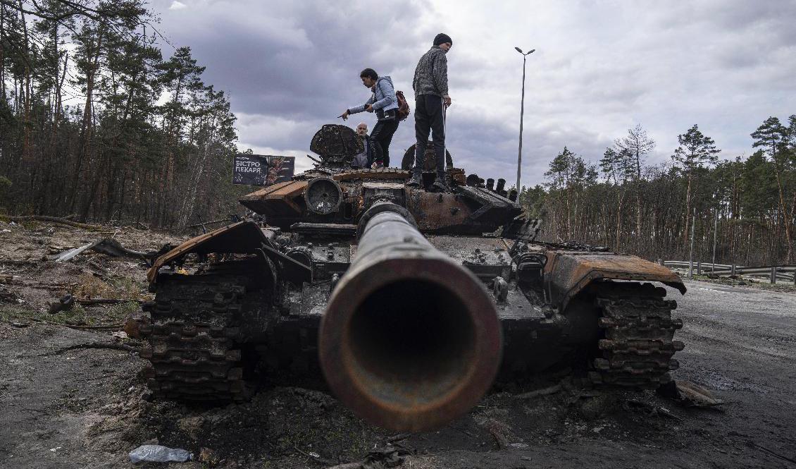 Lokalbor utanför Kiev står på en utslagen rysk stridsvagn. Foto: Evgeniy Maloletka/AP/TT