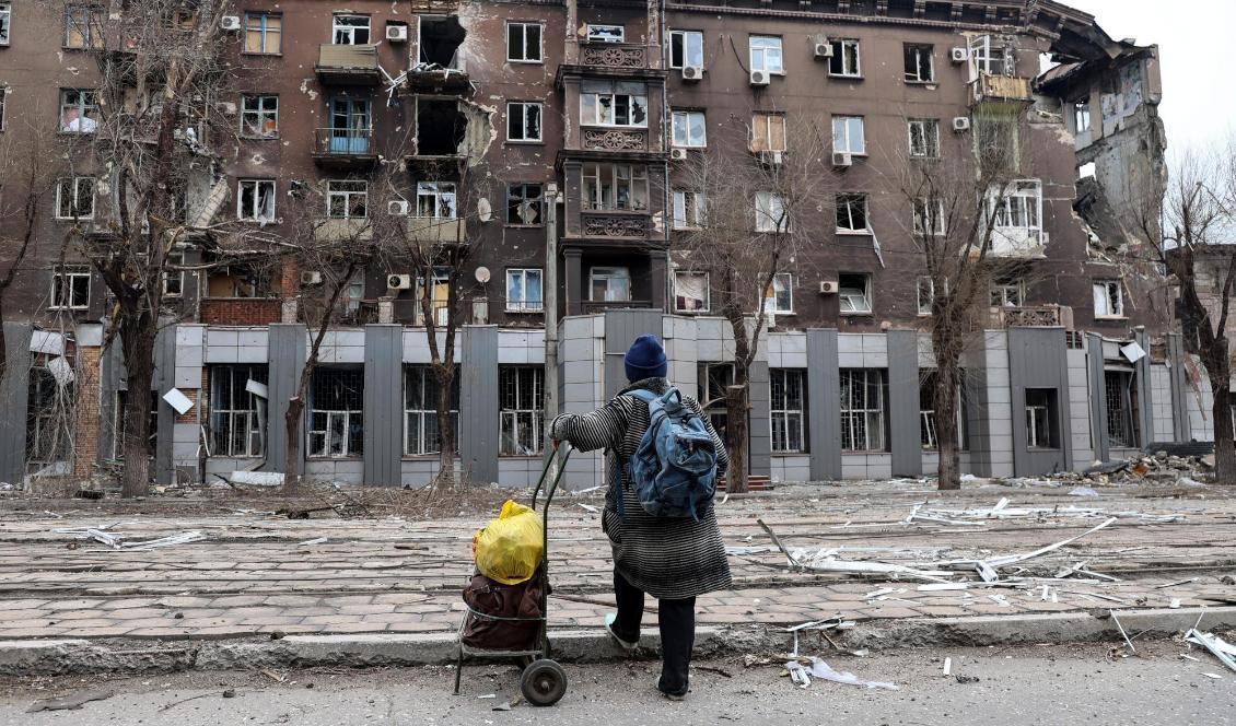 
En boende i den belägrade ukrainska hamnstaden Mariupol tittar på en av de byggnader som förstörts sedan Rysslands anfallskrig inleddes den 24 februari. Foto: Alexei Alexandrov/AP/TT                                            