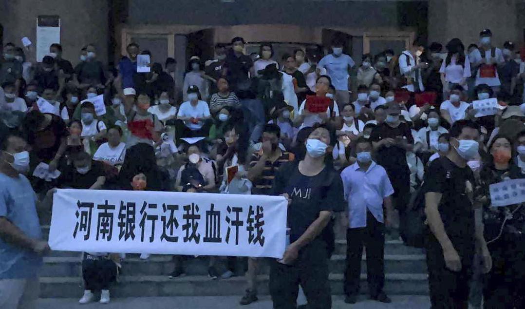 Demonstranter på den trappan utanför en filial till Kinas centralbank i Zhengzhou i Henan-provinsen. Foto: Yang/AP/TT