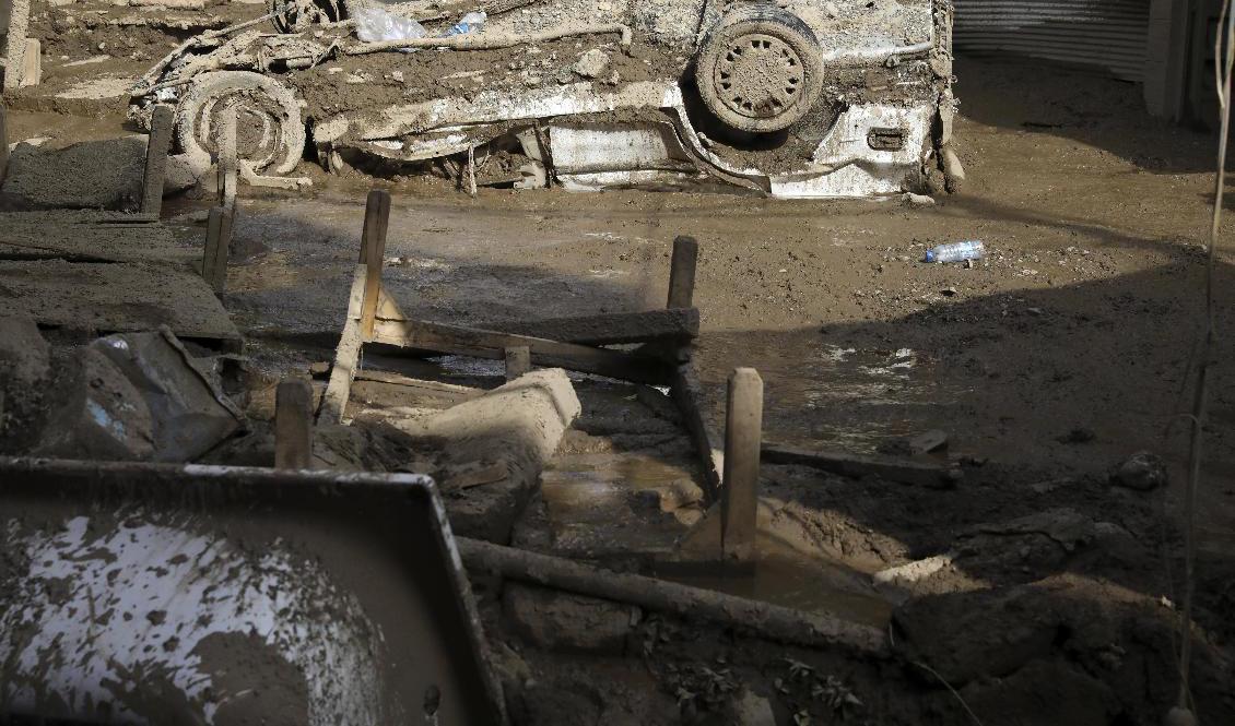 En skadad bil som sitter fast i lera efter översvämningar i den nordvästra delen av Teheran. Foto: Vahid Salemi/AP/TT