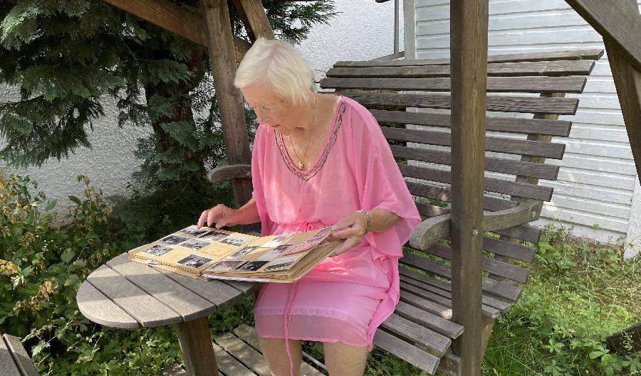 Eeva Jacobson sitter i sin trädgård i Linköping och tittar på gamla foton från det tidiga 1940-talet, när hon nyligen hade kommit till Sverige. Foto: Göran Jacobson