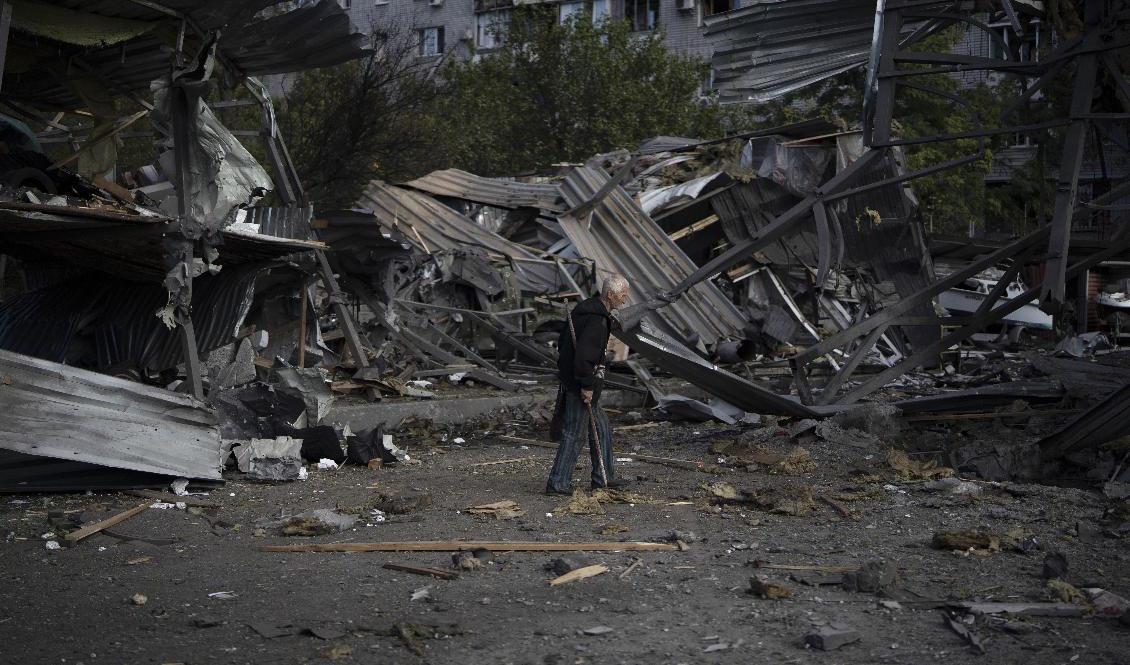 En äldre man går förbi en butik som förstörts i en rysk attack mot Zaporizjzja den 11 oktober. Foto: Leo Correa/AP/TT