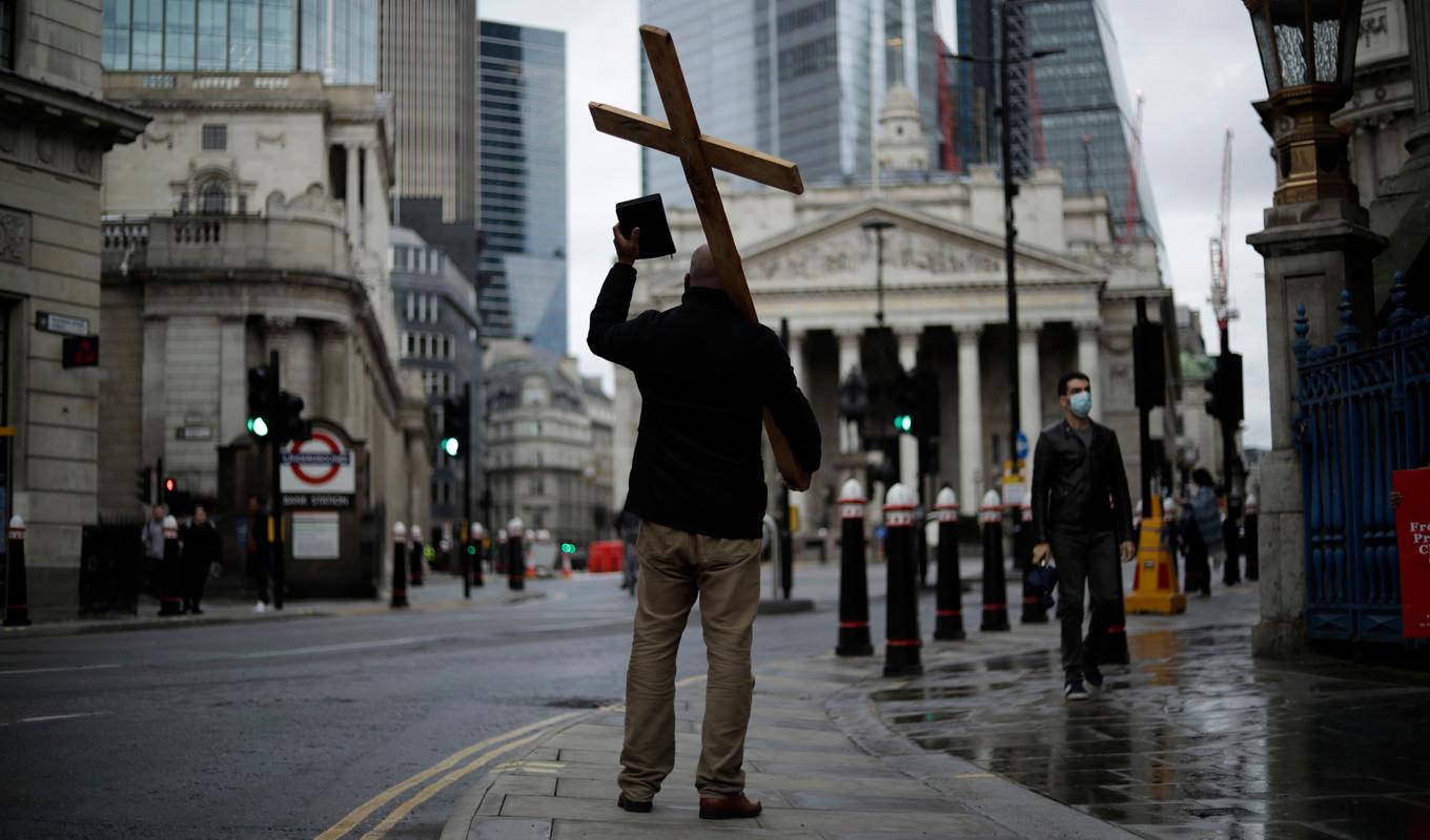 En man med ett stort kors predikar på egen hand i centrala London. Arkivbild från november 2020. Foto: Matt Dunham/AP/TT
