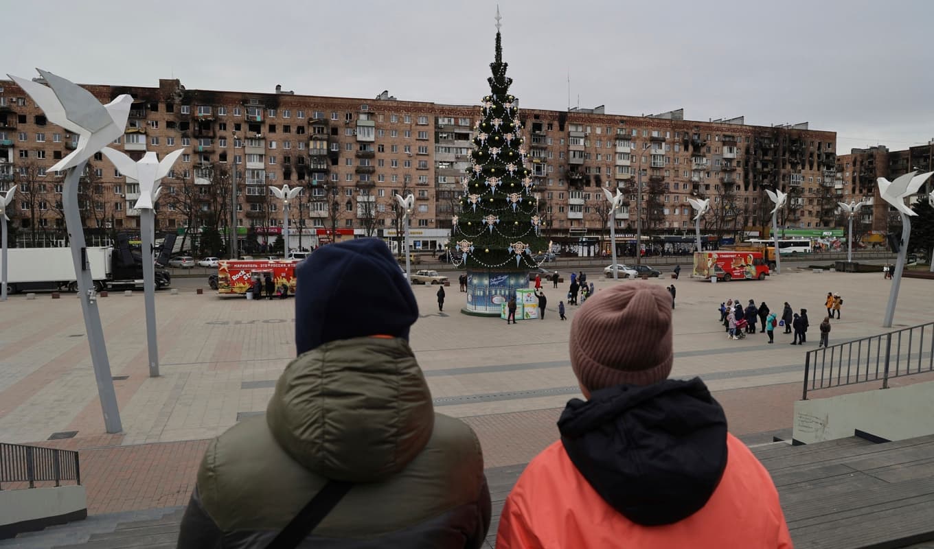 Mariupolbor vid ett torg med en julgran som pyntats för den ryskortodoxa julen på torsdagen. Foto: Alexei Alexandrov/AP/TT