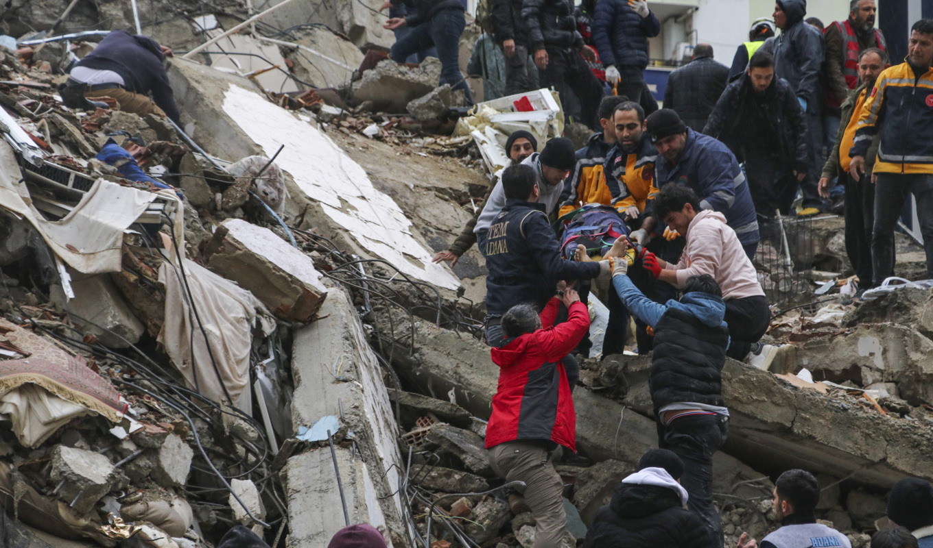 En människa räddas ur rasmassorna som återstår av ett flerfamiljshus i den turkiska staden Adana. Foto: IHA via AP/TT