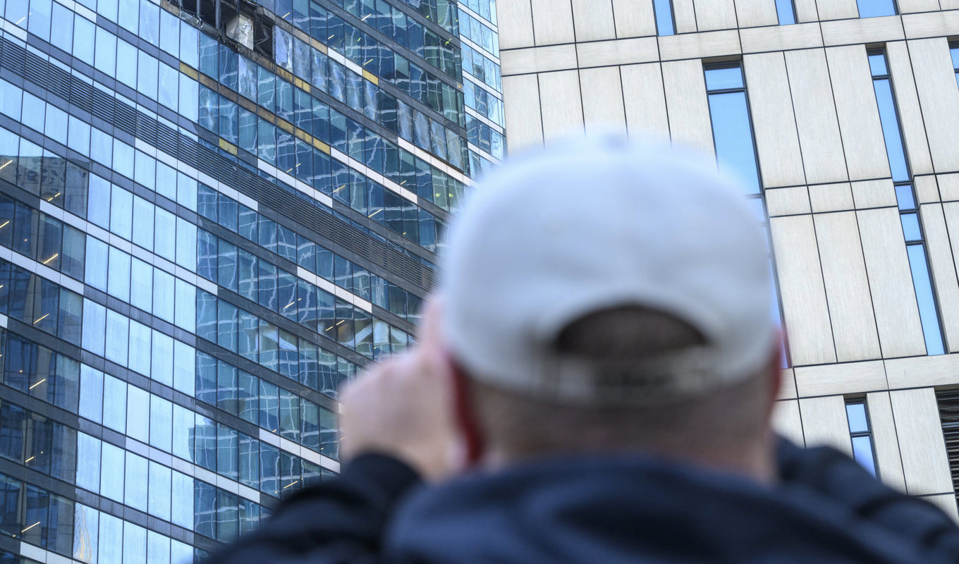 En man fotograferar skadorna efter att en drönarattack träffat en byggnad i Moskvas affärsdistrikt. Foto: AP/TT